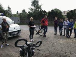 Na zdjęciu widać grupę osób, jest to profilaktyk społeczny KPP w Ostrzeszowie oraz kilku uczestników rajdu. Także na zdjęciu widać pojazd Straży Miejskiej