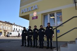 Funkcjonariusze Policji stoją przed budynkiem Posterunku Policji